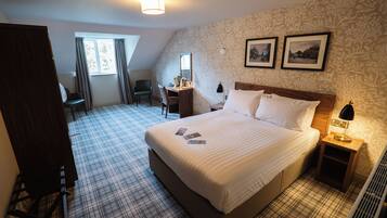 A hotel room with a large bed, a desk, a chair, and a window.