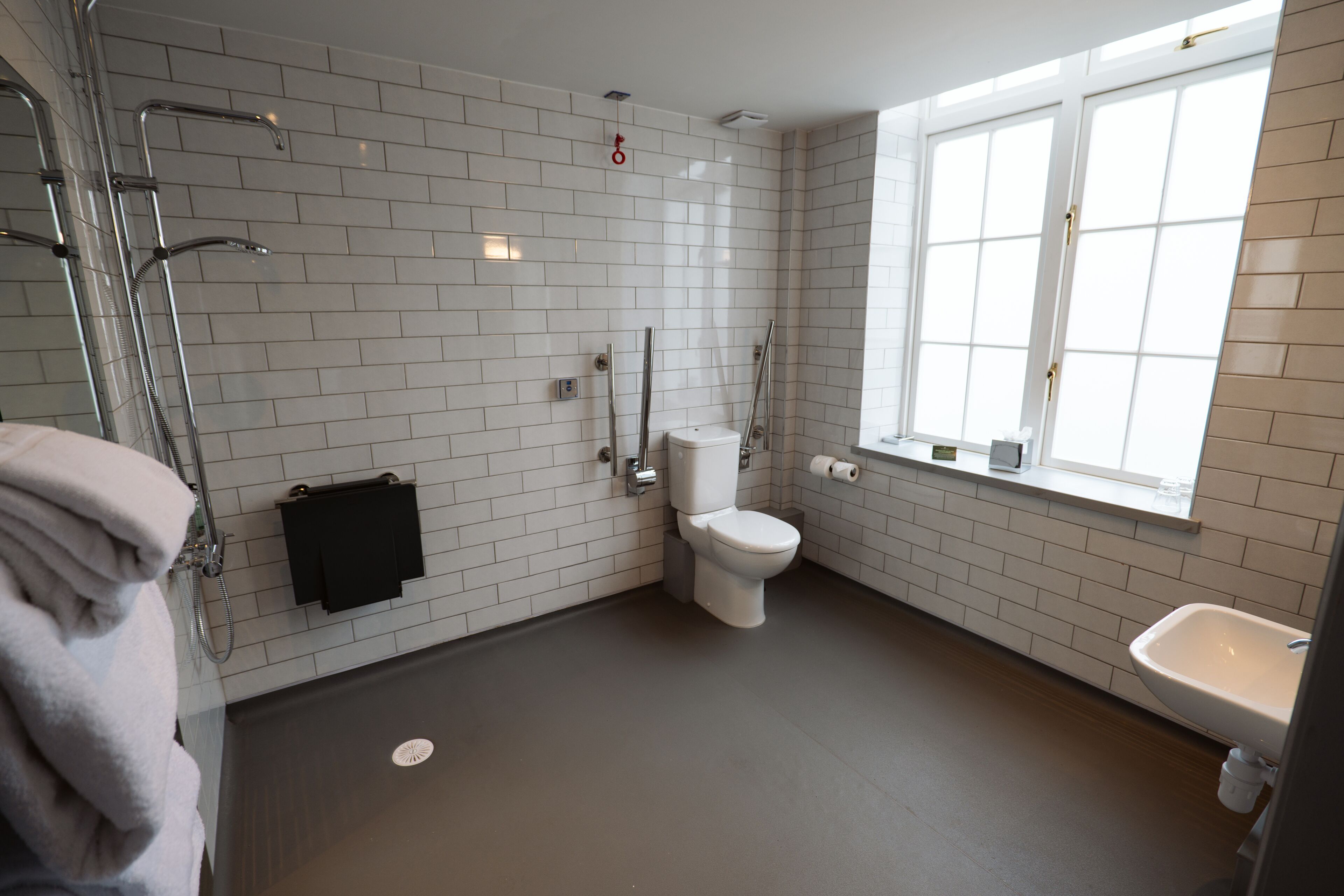 A modern bathroom with white subway tiles, a toilet, a sink, and a shower.