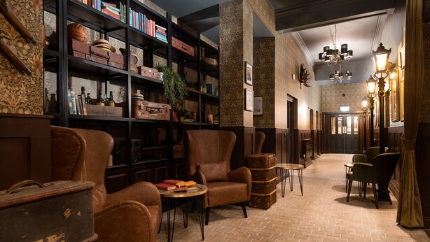 A lobby with leather armchairs, a bookshelf, and a brick floor. - The Ripon Inn - The Inn Collection Group (Ripon)