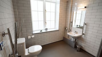A modern bathroom with white subway tiles, a toilet, a sink, and a window.