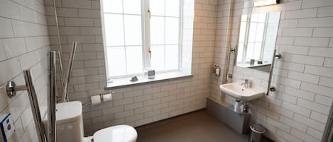 A modern bathroom with white subway tiles, a toilet, a sink, and a window.