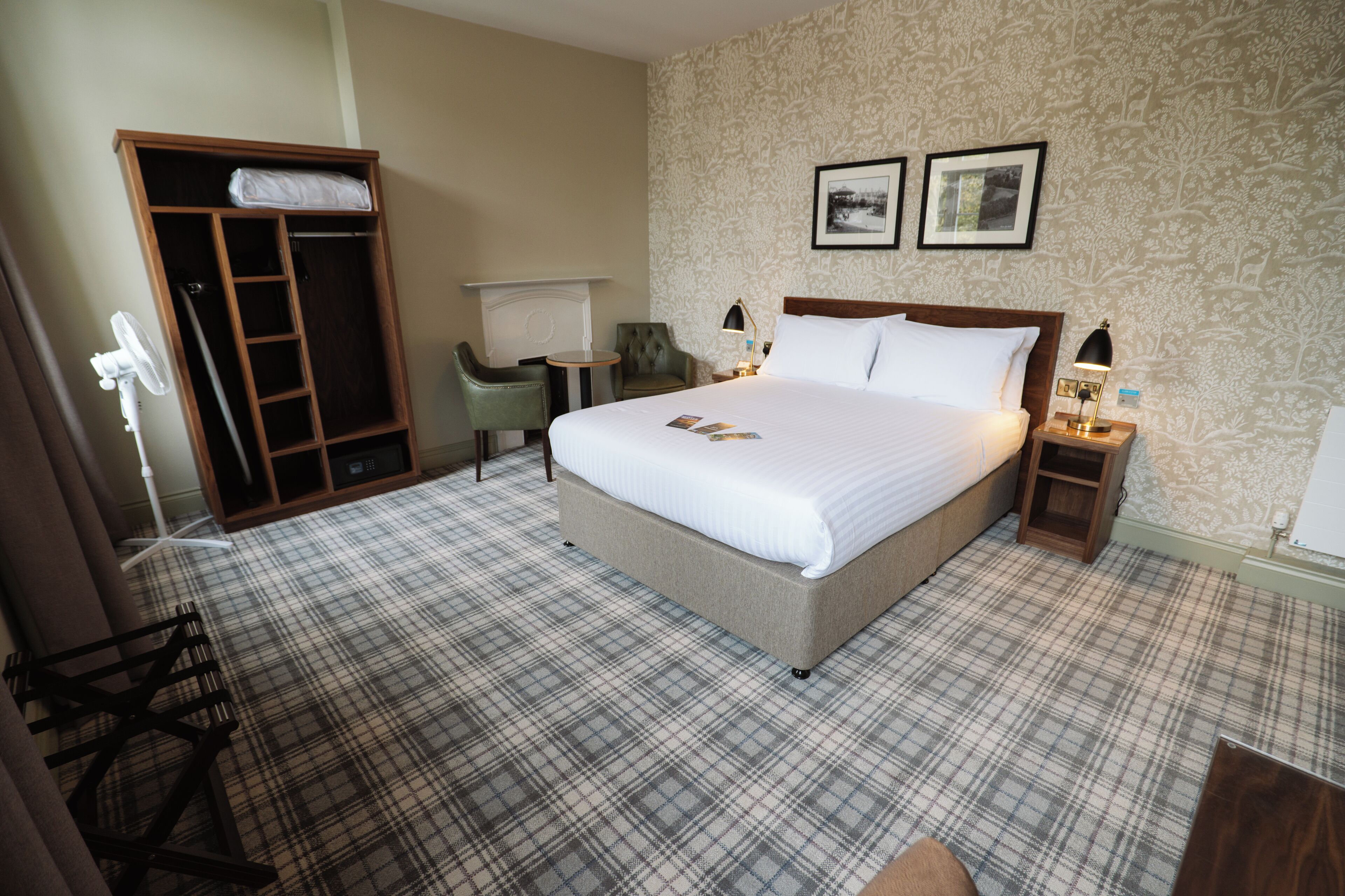 Een hotelkamer met een groot bed, een kledingkast, een bureau en een stoel.