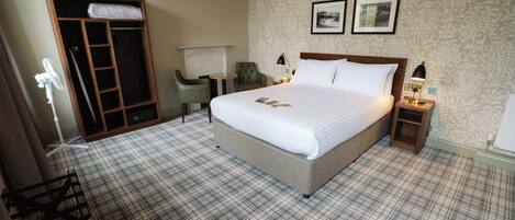 Een hotelkamer met een groot bed, een kledingkast, een bureau en een stoel.