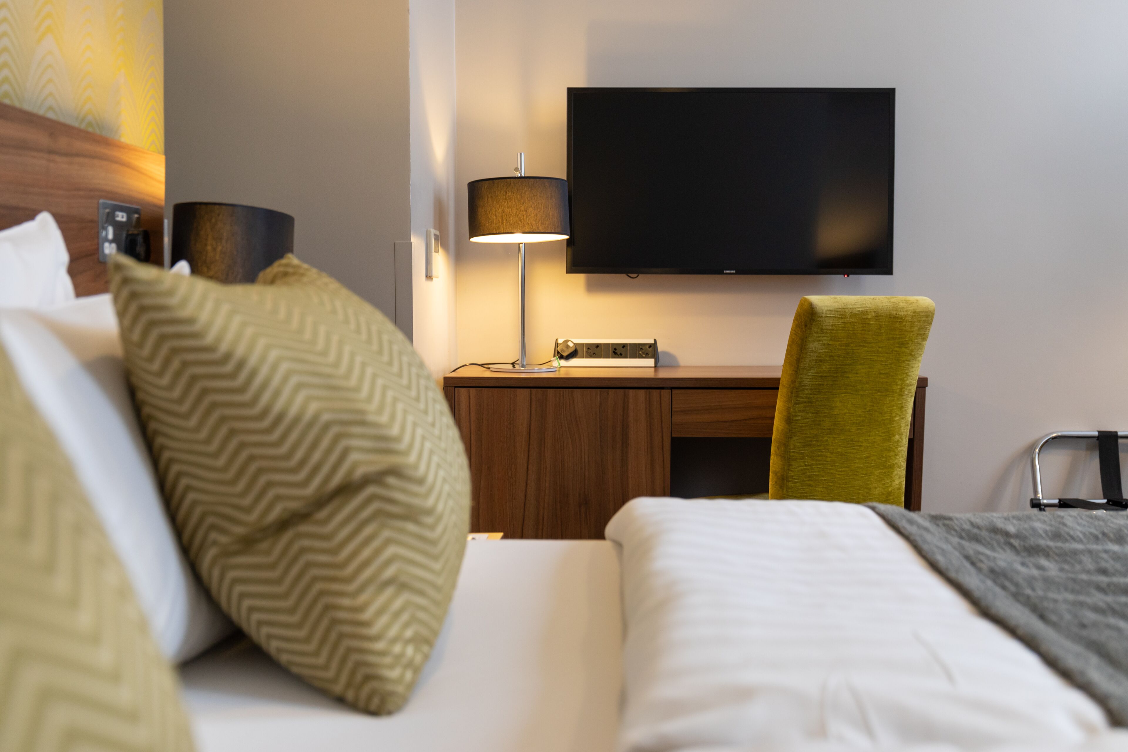 Una habitación de hotel con cama, escritorio, televisor y silla.