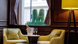 A room with two armchairs, a small table with a champagne bottle, two wine glasses, and a lamp. - Best Western Mornington Hotel London Hyde Park (London)