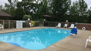 Piscina con zona delimitada por una valla, sillas de descanso y un cartel con los horarios.