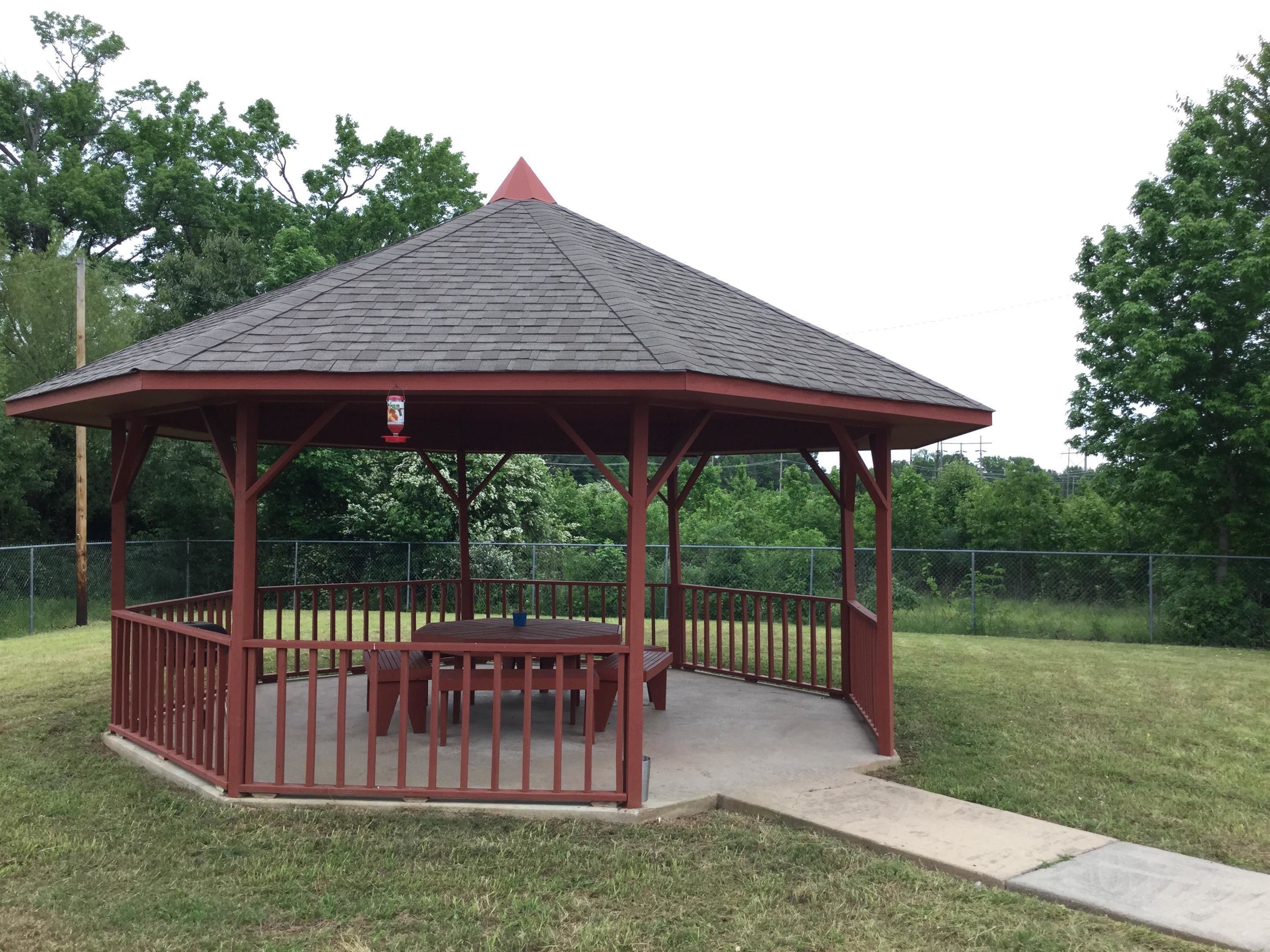 A gazebo with a red roof and wooden benches.
