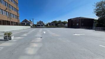 An empty parking lot with directional arrows, surrounded by buildings and a clear sky.