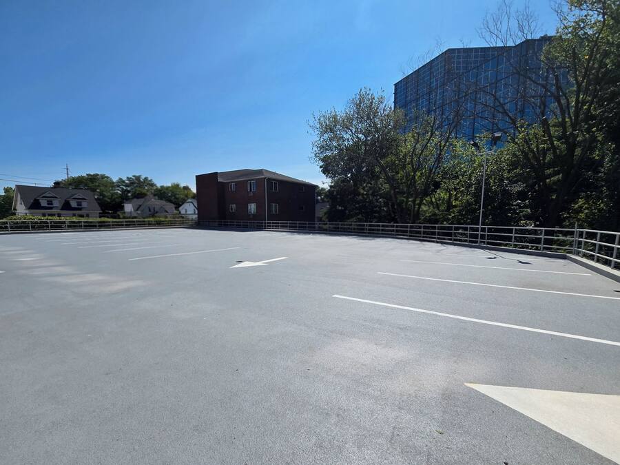 A parking lot with clear lane markings and a white fence.