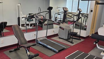 A gym with treadmills, a stationary bike, and a bench.