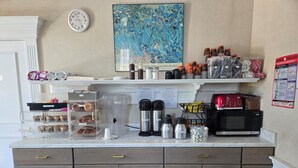 A kitchenette with a coffee machine, milk thermos, sugar container, and a microwave. - Amsterdam Hotel (Stamford)