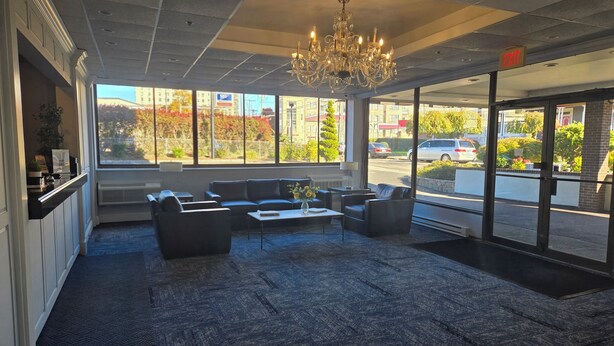 A lobby with a chandelier, seating area, and large windows offering a view of the street. - Amsterdam Hotel (Stamford)
