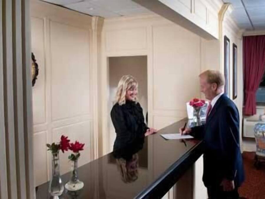 Et receptionsområde med reception, en vase med blomster og et vindue med udsigt.