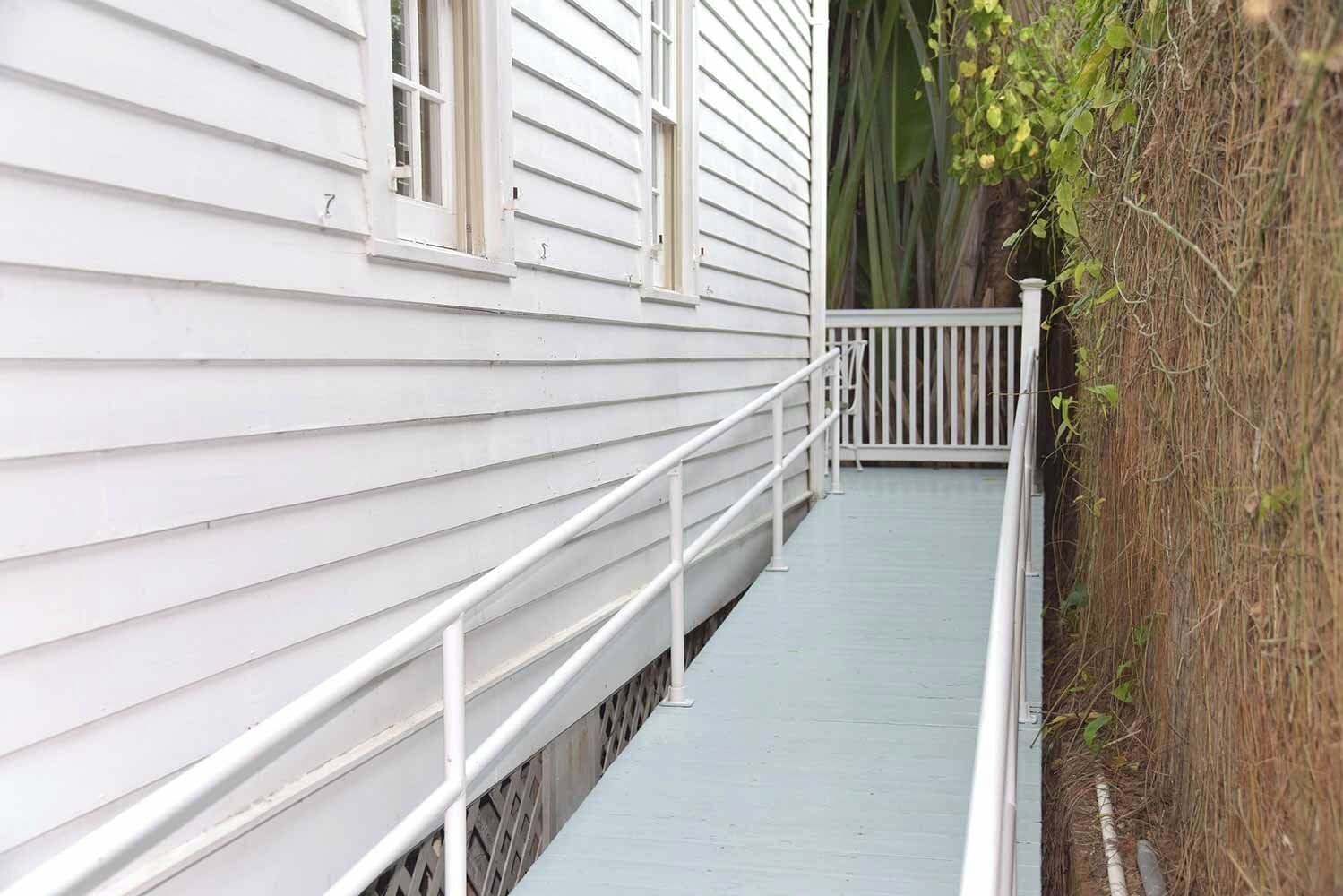 A white wooden house with a small porch and a white railing.