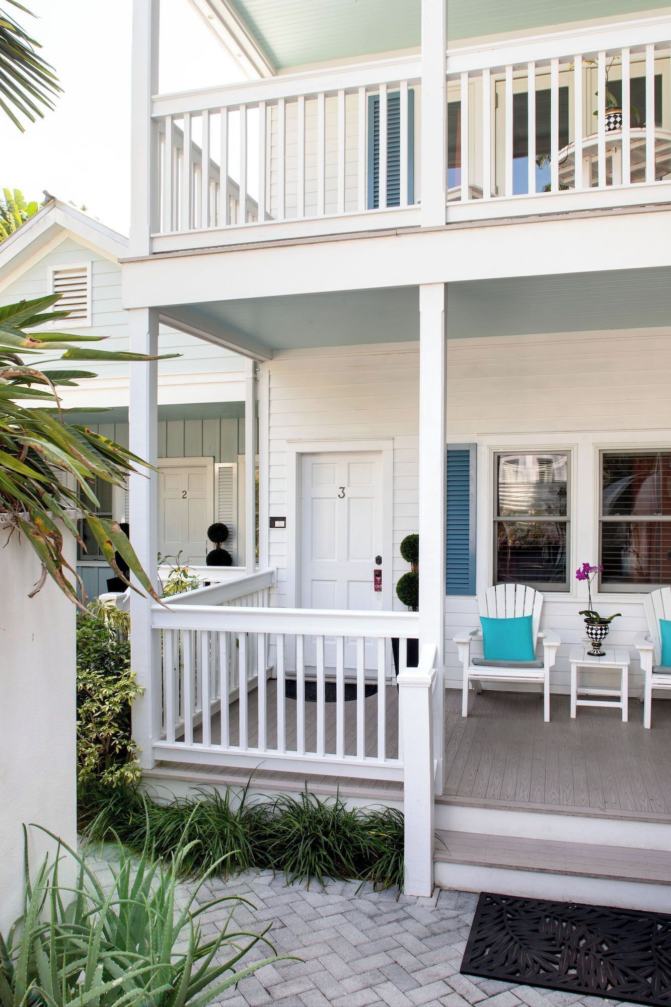 A two-story house with a covered porch, white railings, and a door marked with the number 3.