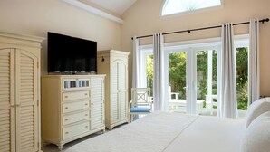 A bedroom with a large bed, a television on a dresser, and a view of the outdoors through a sliding door. - The Gardens Hotel (Key West)