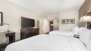 Ein Hotelzimmer mit einem großen Bett, einem Schreibtisch mit Stuhl, einem Fernseher und einem Kleiderschrank.