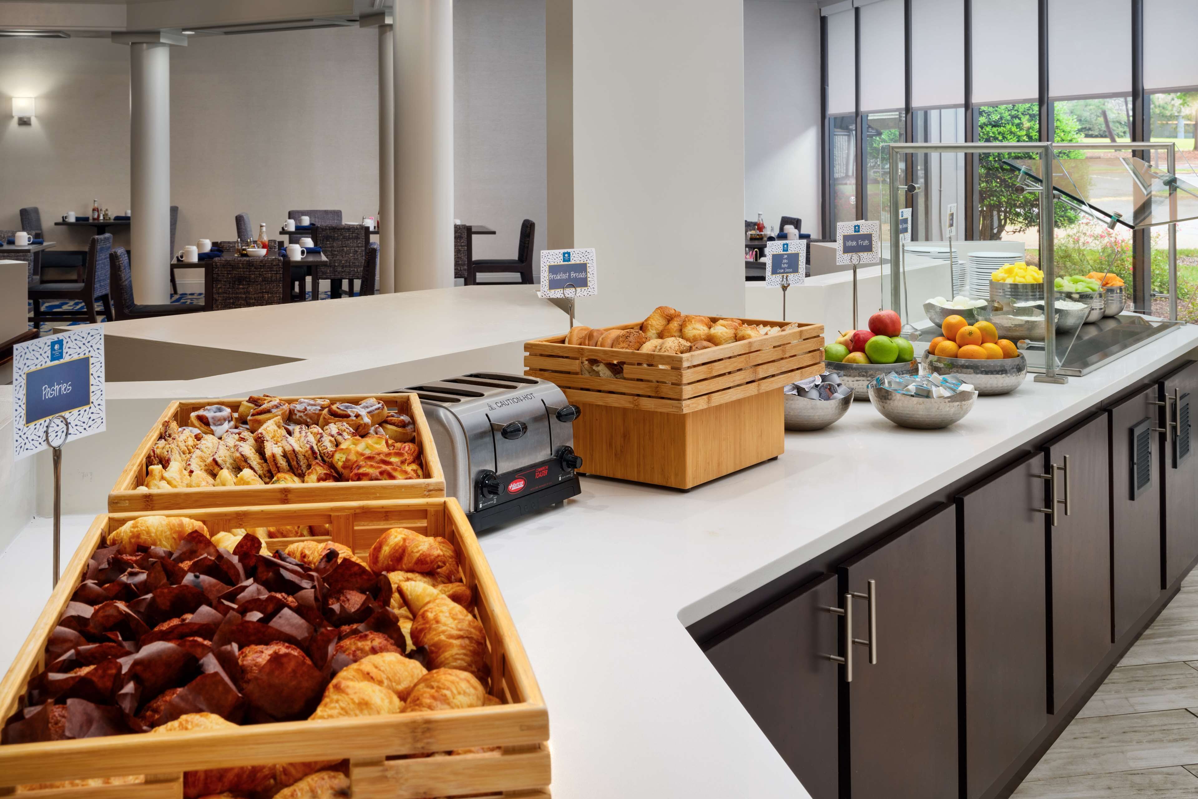 A buffet area with various food options, including pastries, fruits, and a coffee machine.