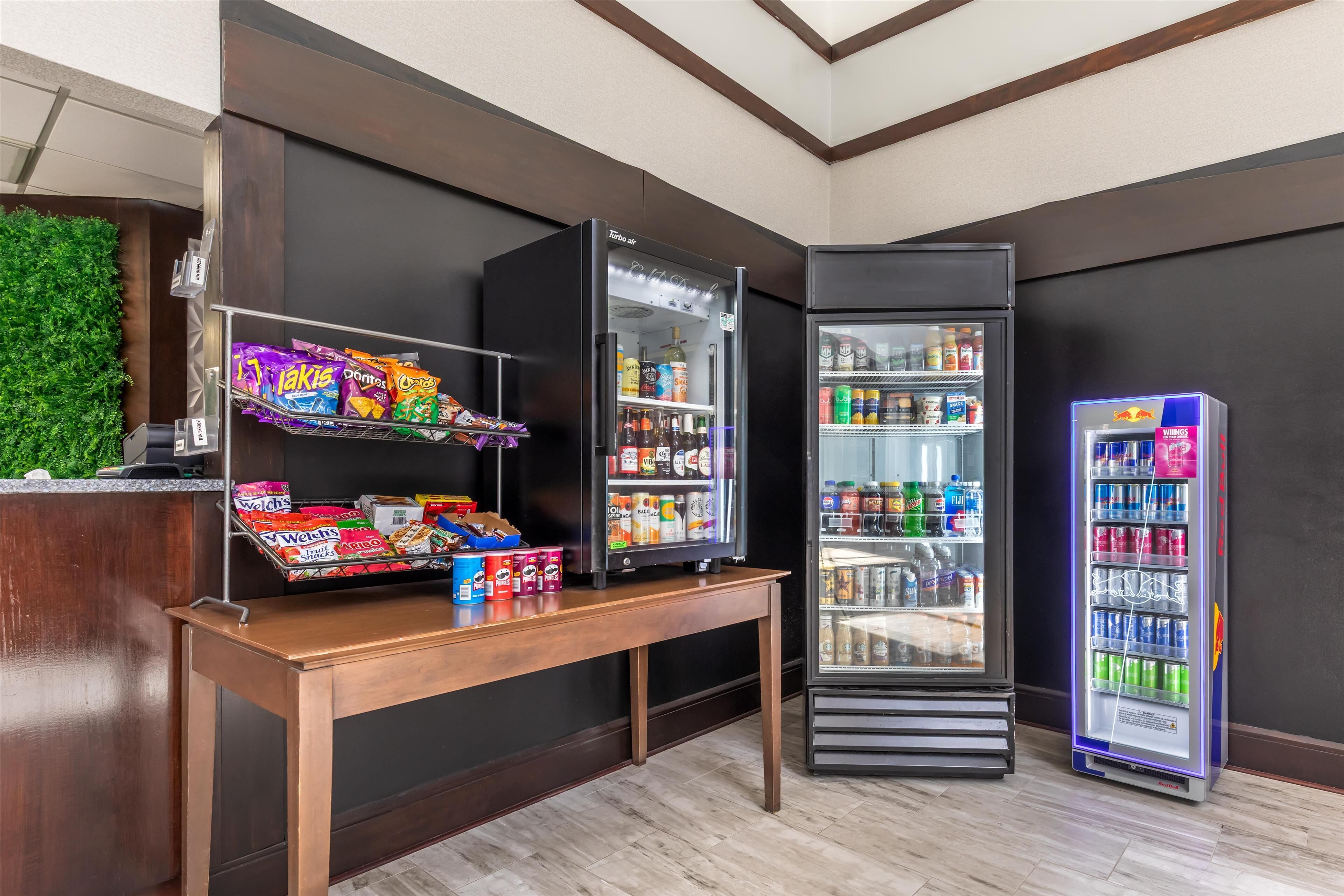Una estación autoservicio de aperitivos y bebidas con una variedad de opciones, incluyendo papas fritas y bebidas embotelladas.