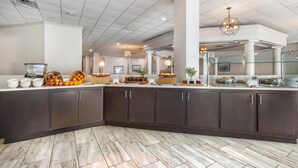 A modern kitchen with dark cabinets, a marble floor, and various food items displayed on the counter. - DoubleTree by Hilton Williamsburg (Williamsburg)