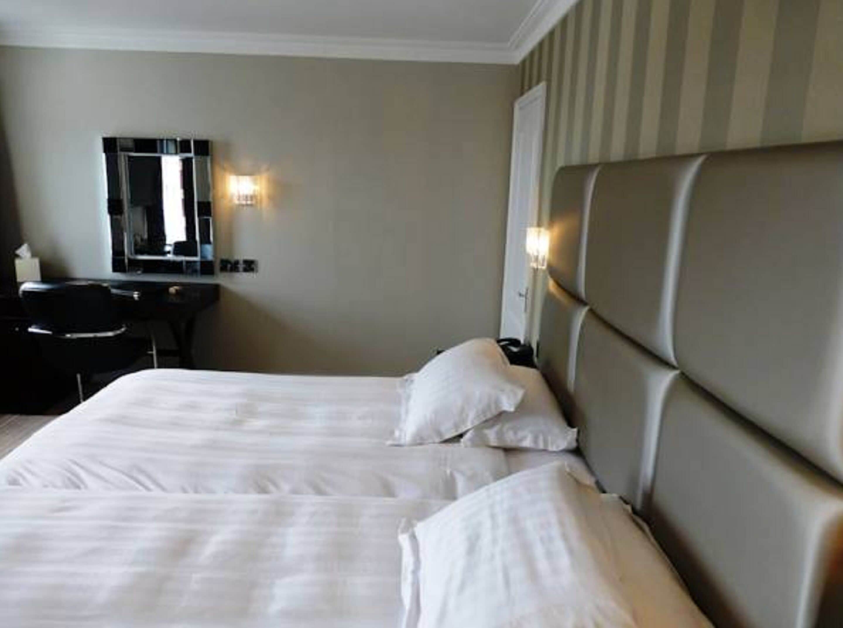 A hotel room with a large bed, a desk, and a mirror.