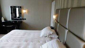 A hotel room with a large bed, a desk, and a mirror.