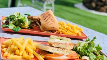 Comida que incluye un sándwich, papas fritas y una ensalada sobre una mesa.