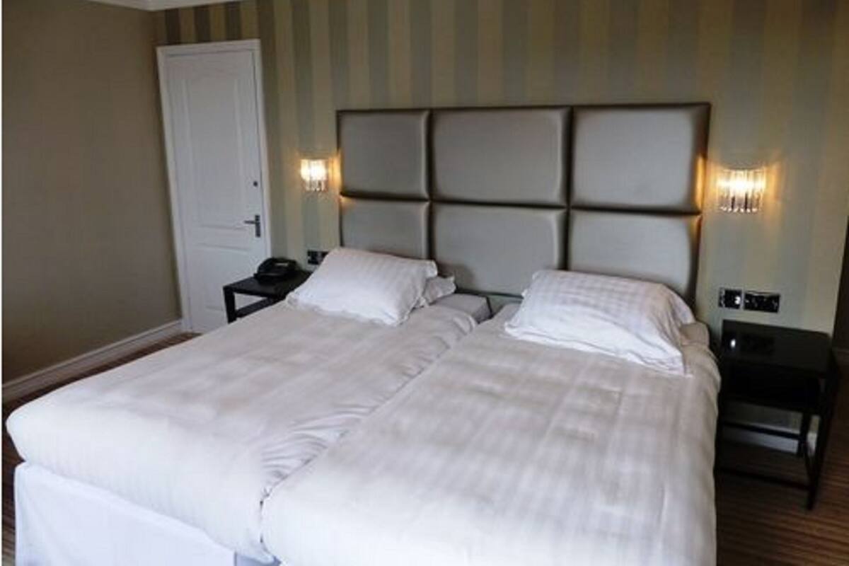 A double bed with a headboard, two bedside tables, and wall-mounted lamps.