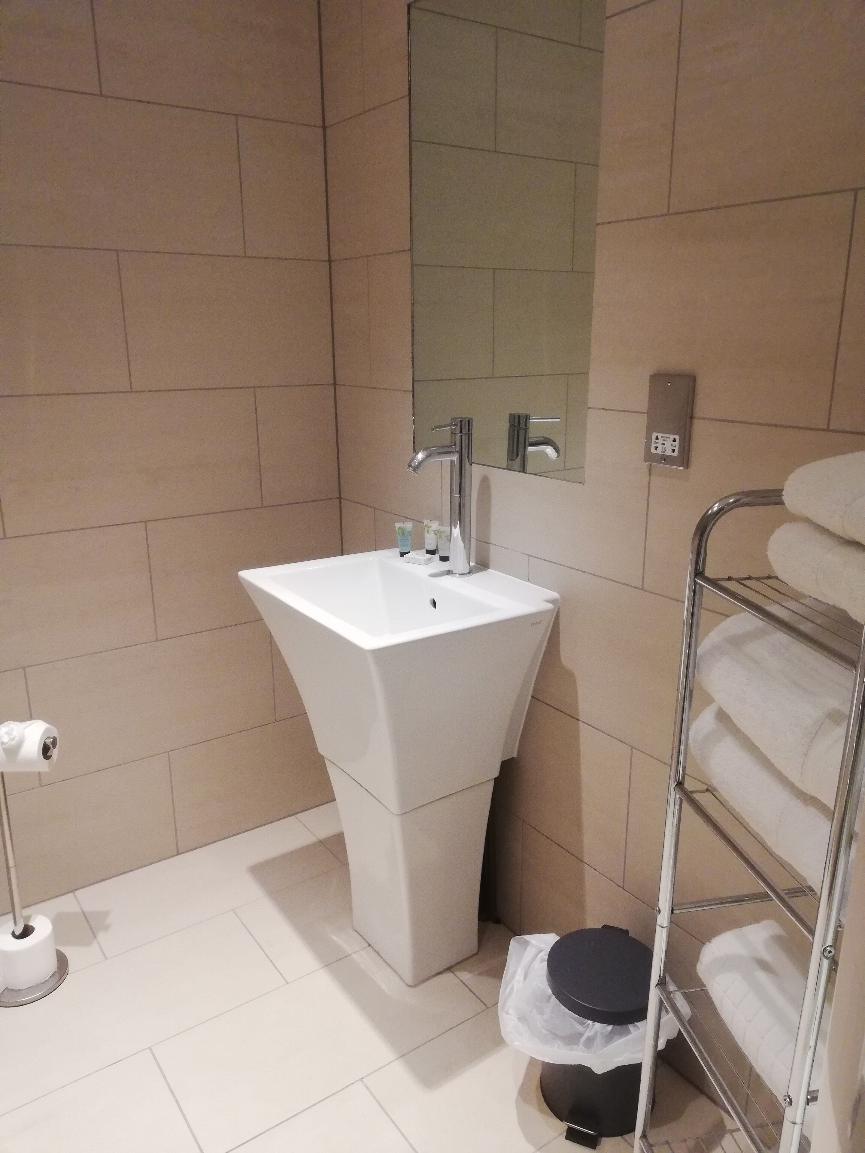 A bathroom with a white sink, a mirror, a towel rack, and a toilet.