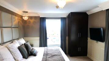 A bedroom with a large bed, a chandelier, a wardrobe, and a television.