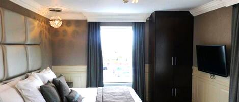 A bedroom with a large bed, a chandelier, a wardrobe, and a television.