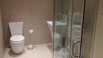 Un baño moderno con inodoro, bidé y cabina de ducha de vidrio.