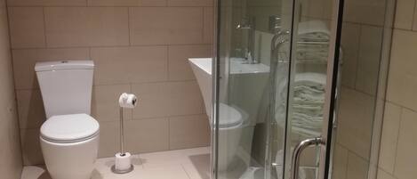 Un baño moderno con inodoro, bidé y cabina de ducha de vidrio.