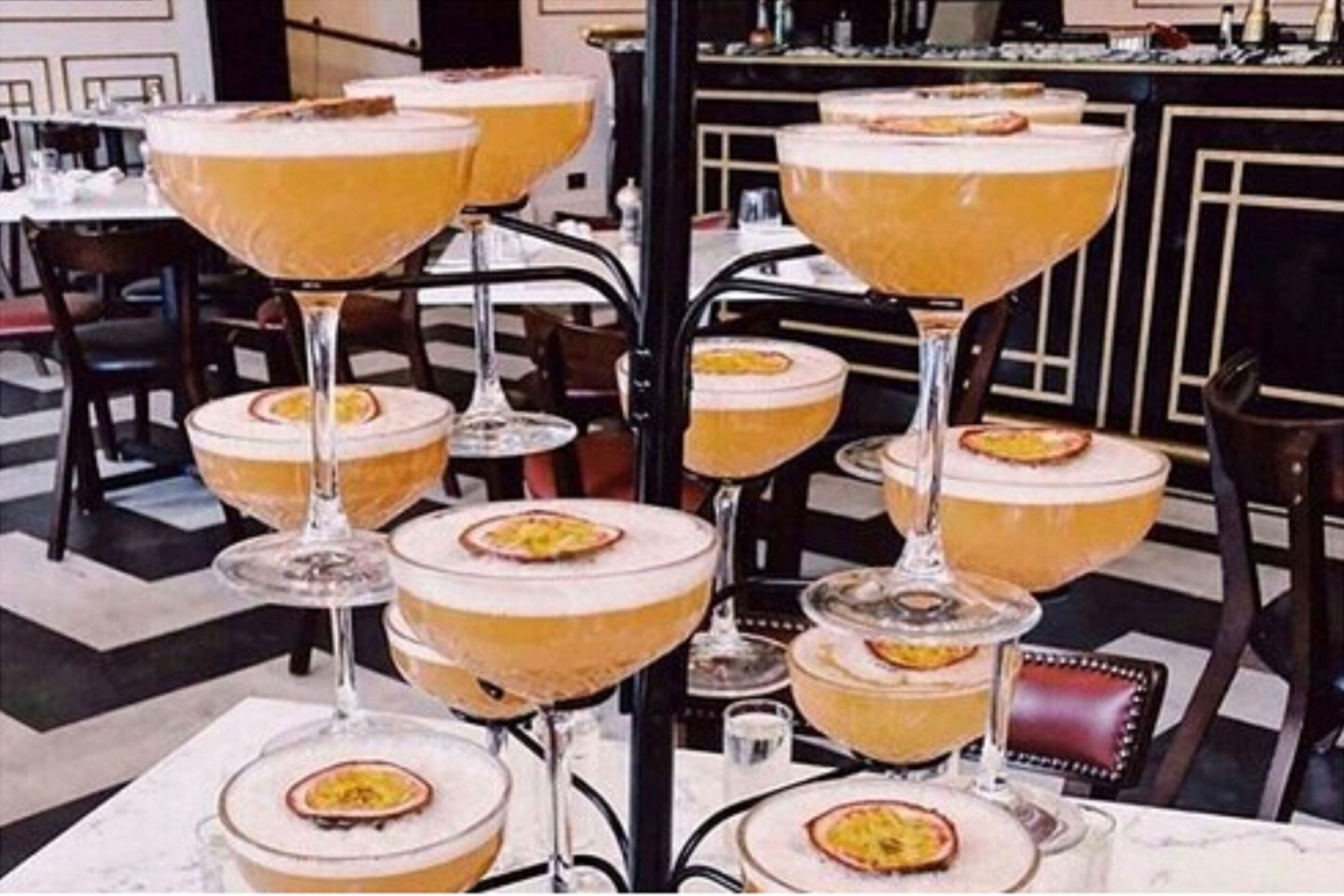 Un'area bar con diversi bicchieri highball colmi di una bevanda gialla, disposti su un espositore.