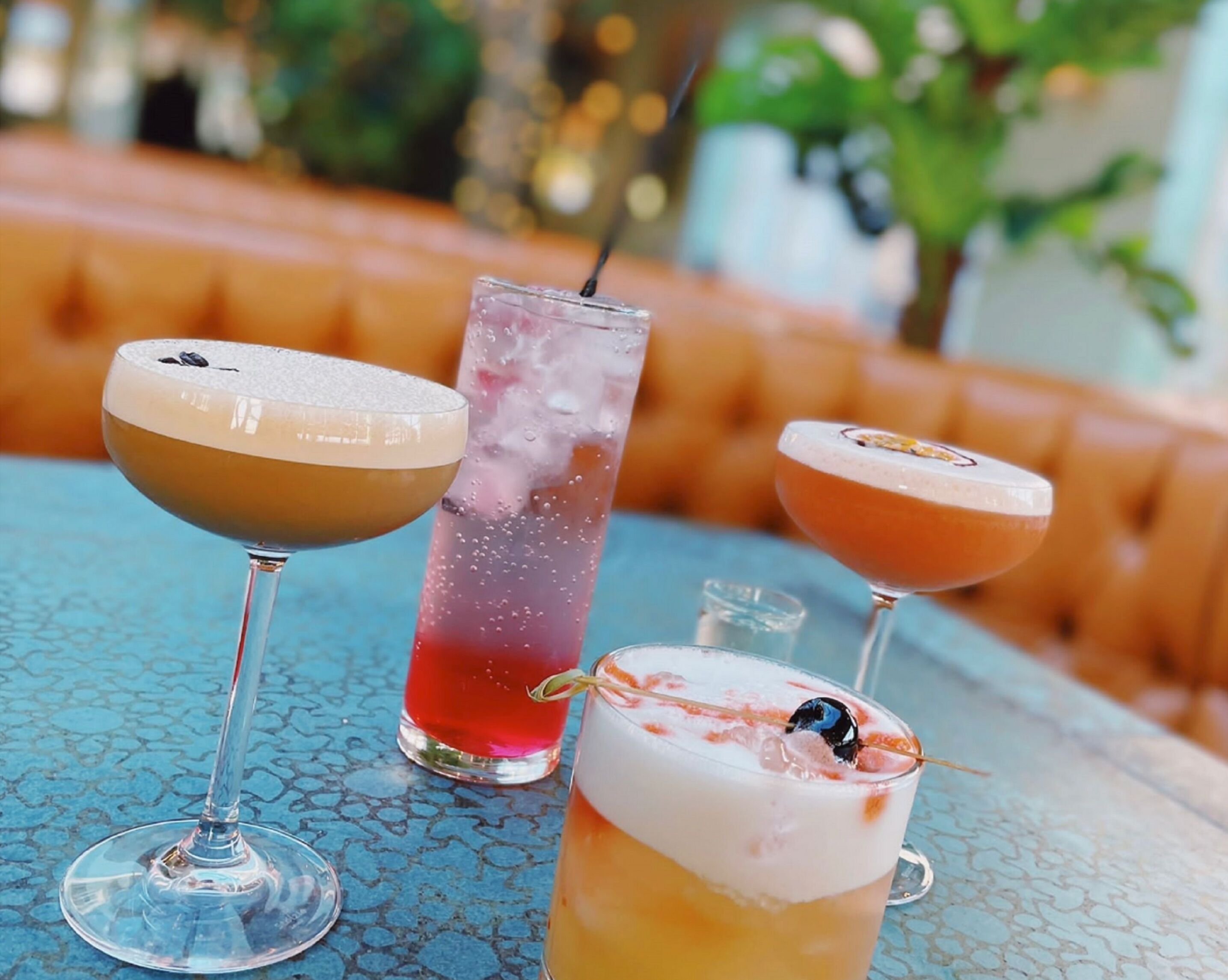 Trois cocktails sont posés sur une table dont le plateau est décoré d’un motif bleu.