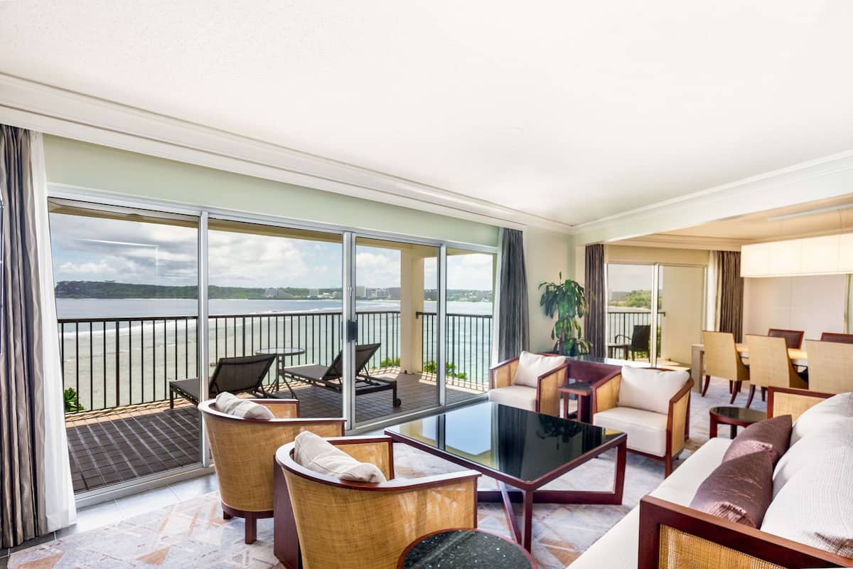 Varanda ampla com vista para o mar, mobiliada com cadeiras e uma mesa.