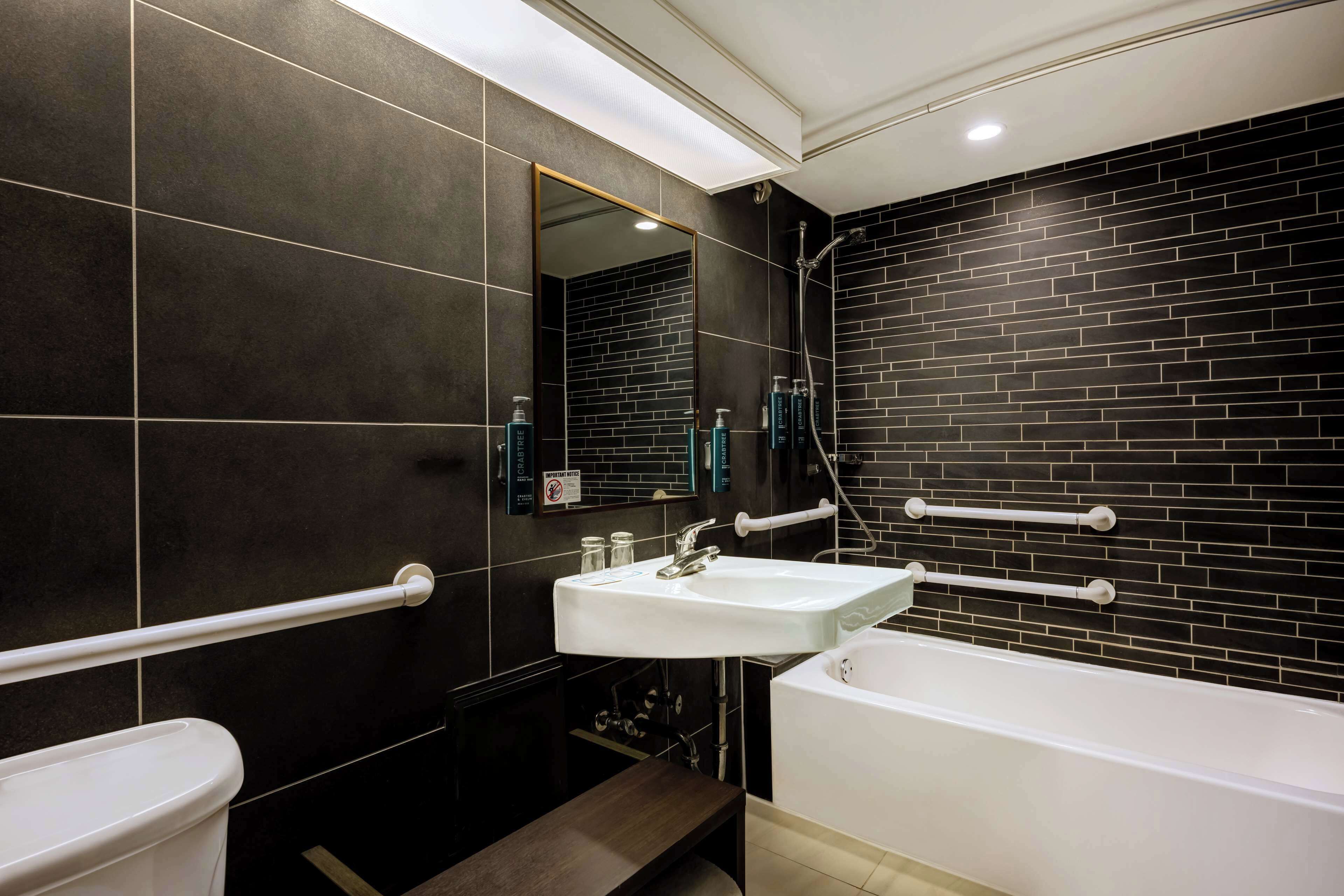 Ein modernes Badezimmer mit einem weißen Waschbecken, einer Badewanne und einem Spiegel.