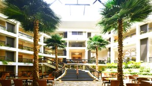 A multi-level atrium with palm trees, a staircase, and outdoor seating areas. - Hilton Guam Resort And Spa (Tamuning)