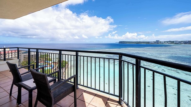 A balcony with a view of the ocean and distant buildings. - Hilton Guam Resort And Spa (Tamuning)