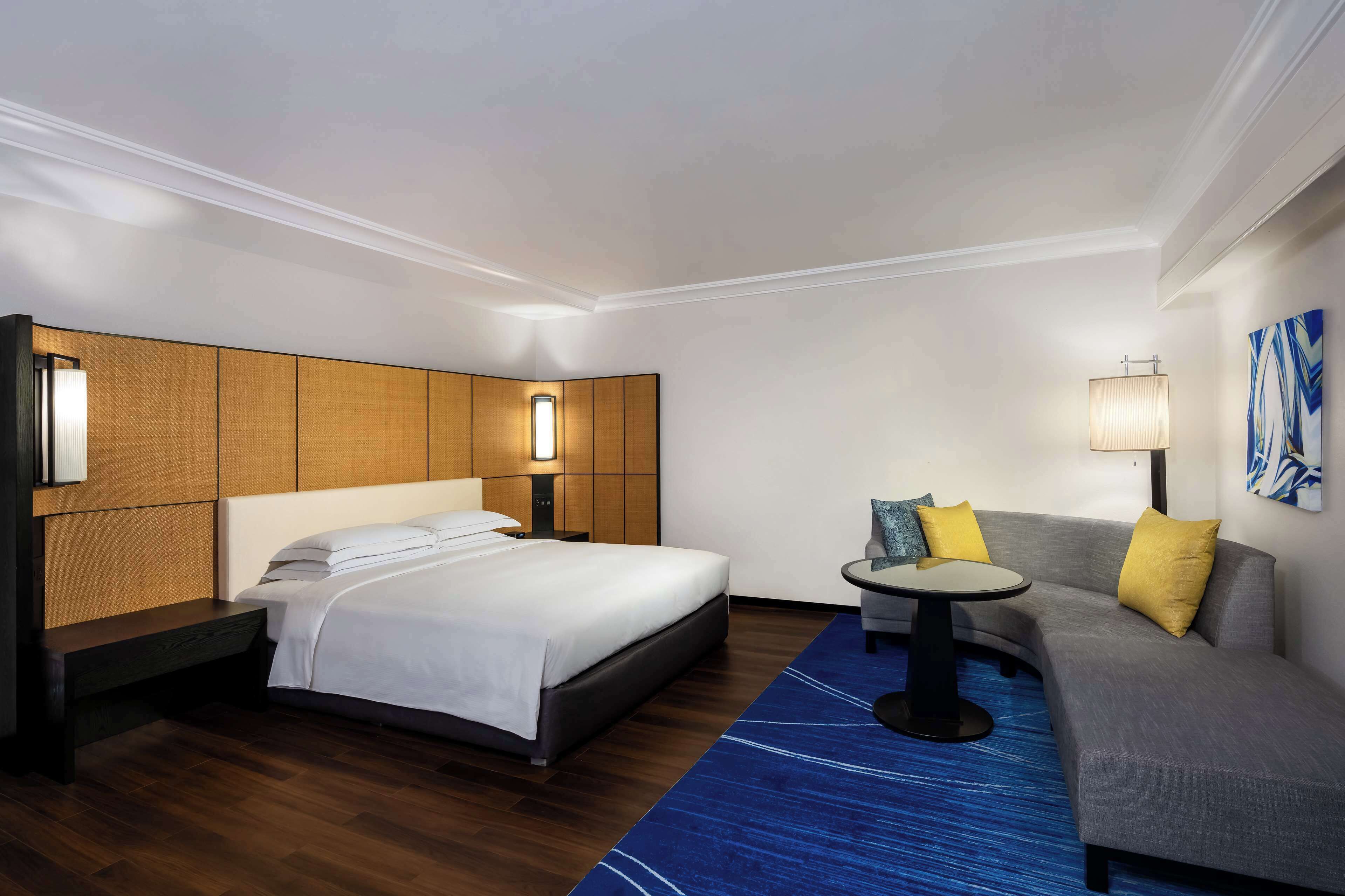 Una habitación de hotel con una cama, un sofá, una mesita y una lámpara.
