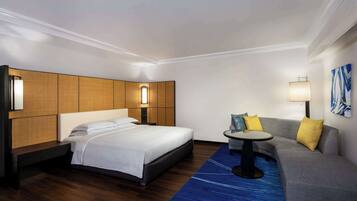 Una habitación de hotel con una cama, un sofá, una mesita y una lámpara.