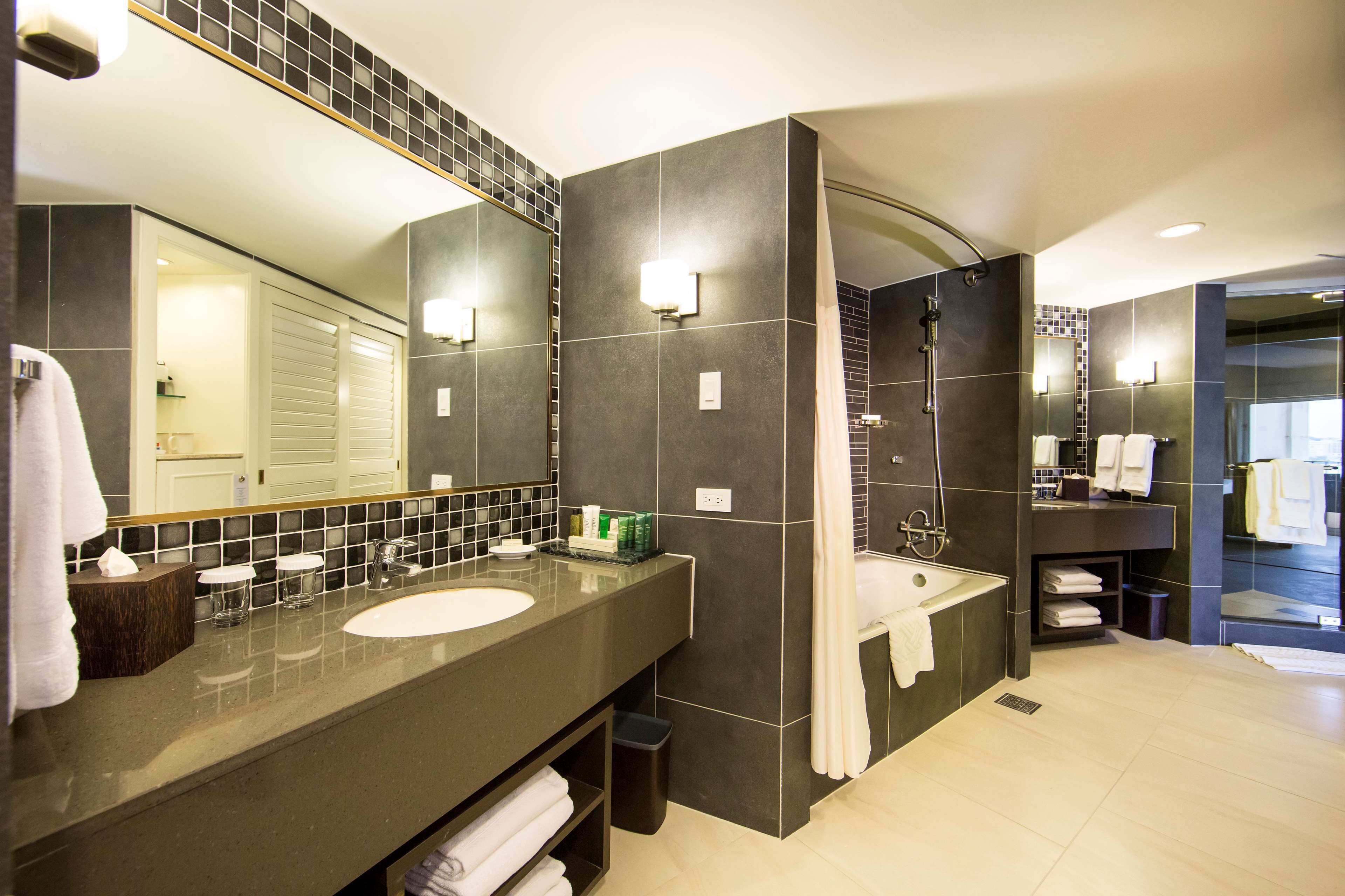 A modern bathroom with two sinks, a large mirror, and a shower area.