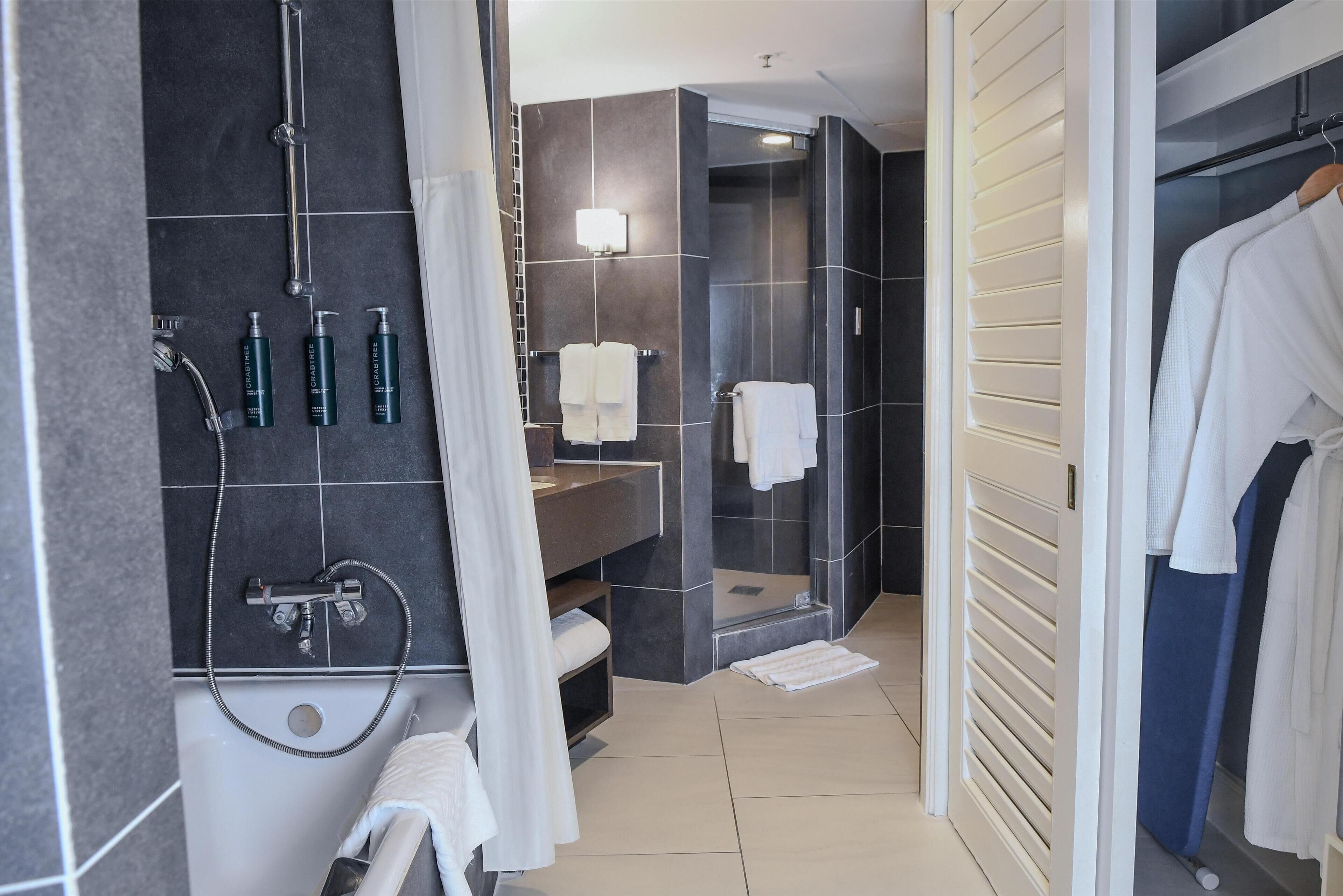 A modern bathroom with a bathtub, shower, and vanity.