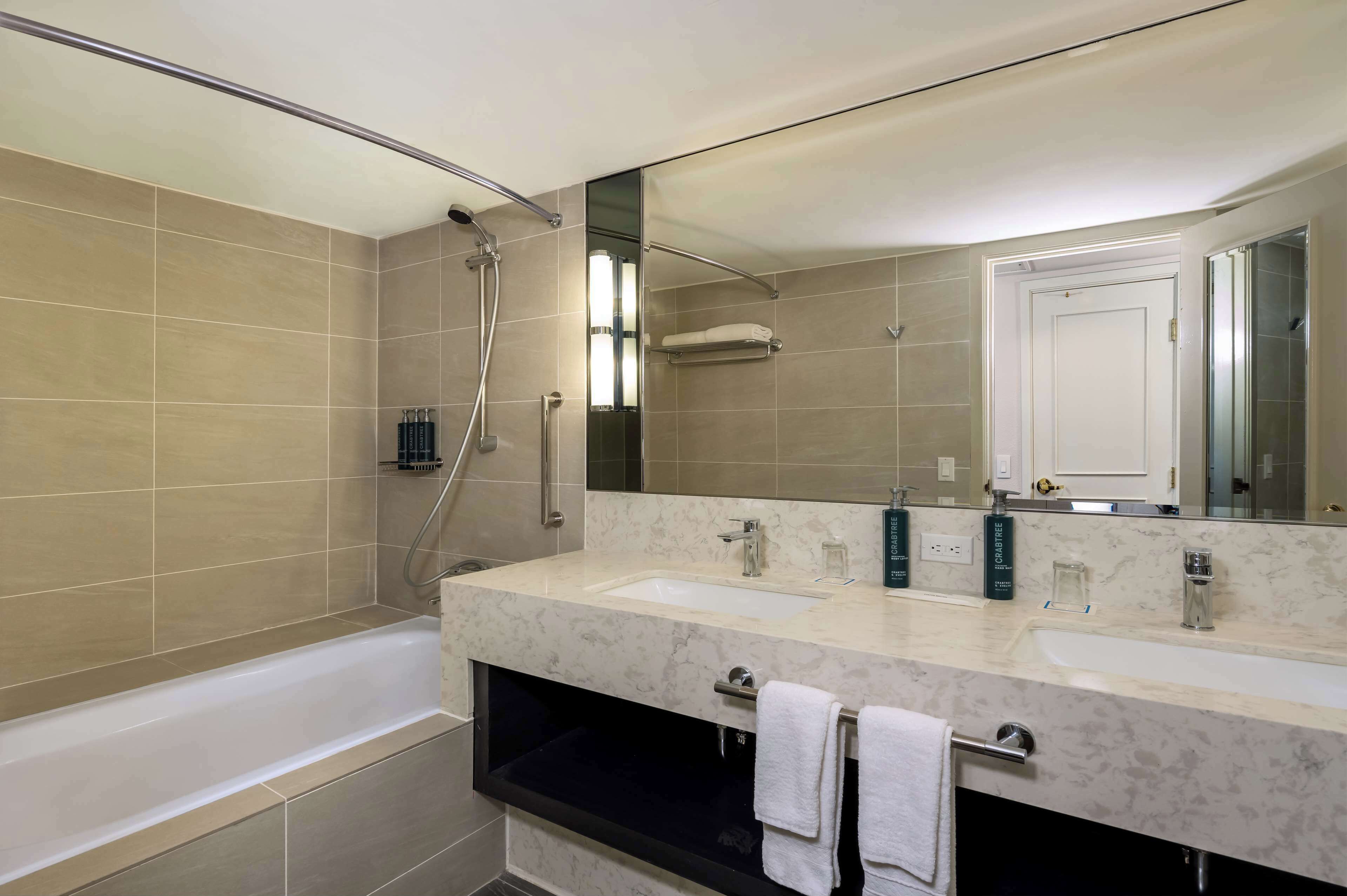 Un baño moderno con dos lavamanos, una bañera y una ducha.