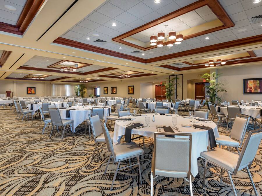 A large conference room with multiple round tables and chairs, arranged in rows.