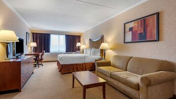 A hotel room with a bed, a sofa, a desk, and a TV.