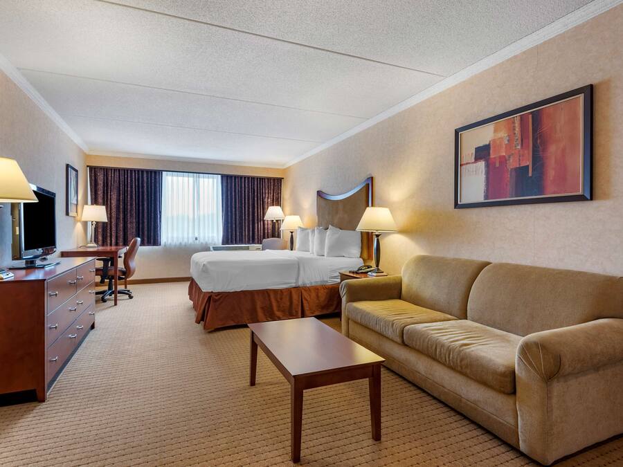 A hotel room with a bed, a sofa, a desk, and a TV.