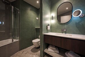 A modern bathroom with a glass-enclosed shower, a toilet, a vanity with a mirror, and a built-in light. - voco Telford - Ironbridge by IHG (Telford)