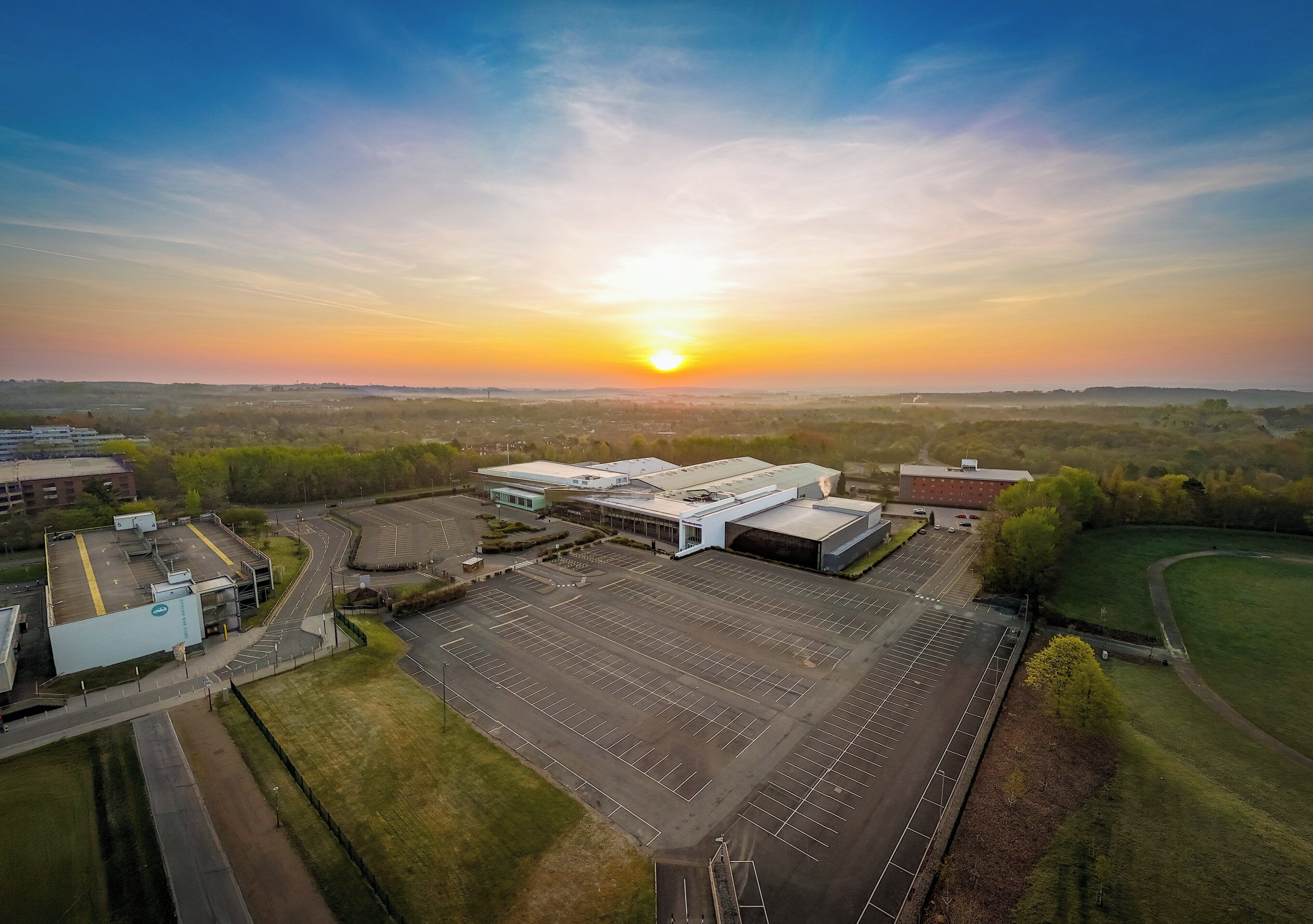 An aerial view of a parking lot and buildings with a sunset in the background.