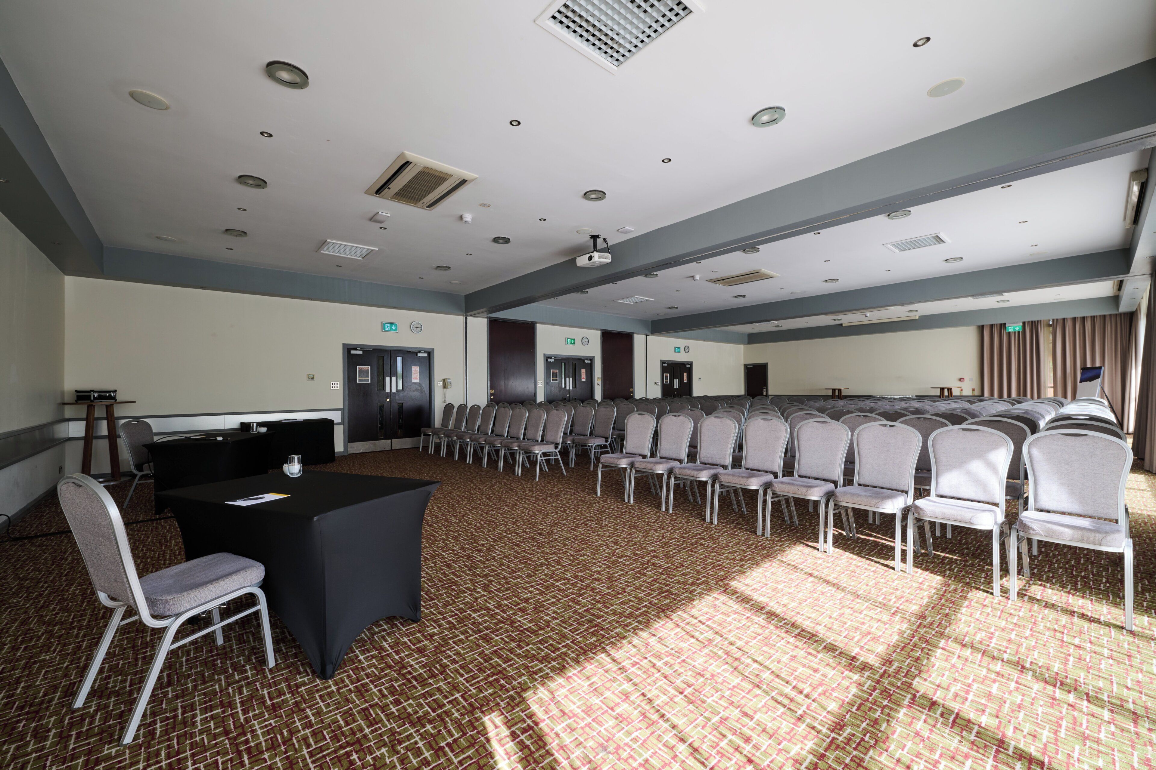 Une salle de conférence avec une longue table, des chaises et un sol recouvert de moquette.